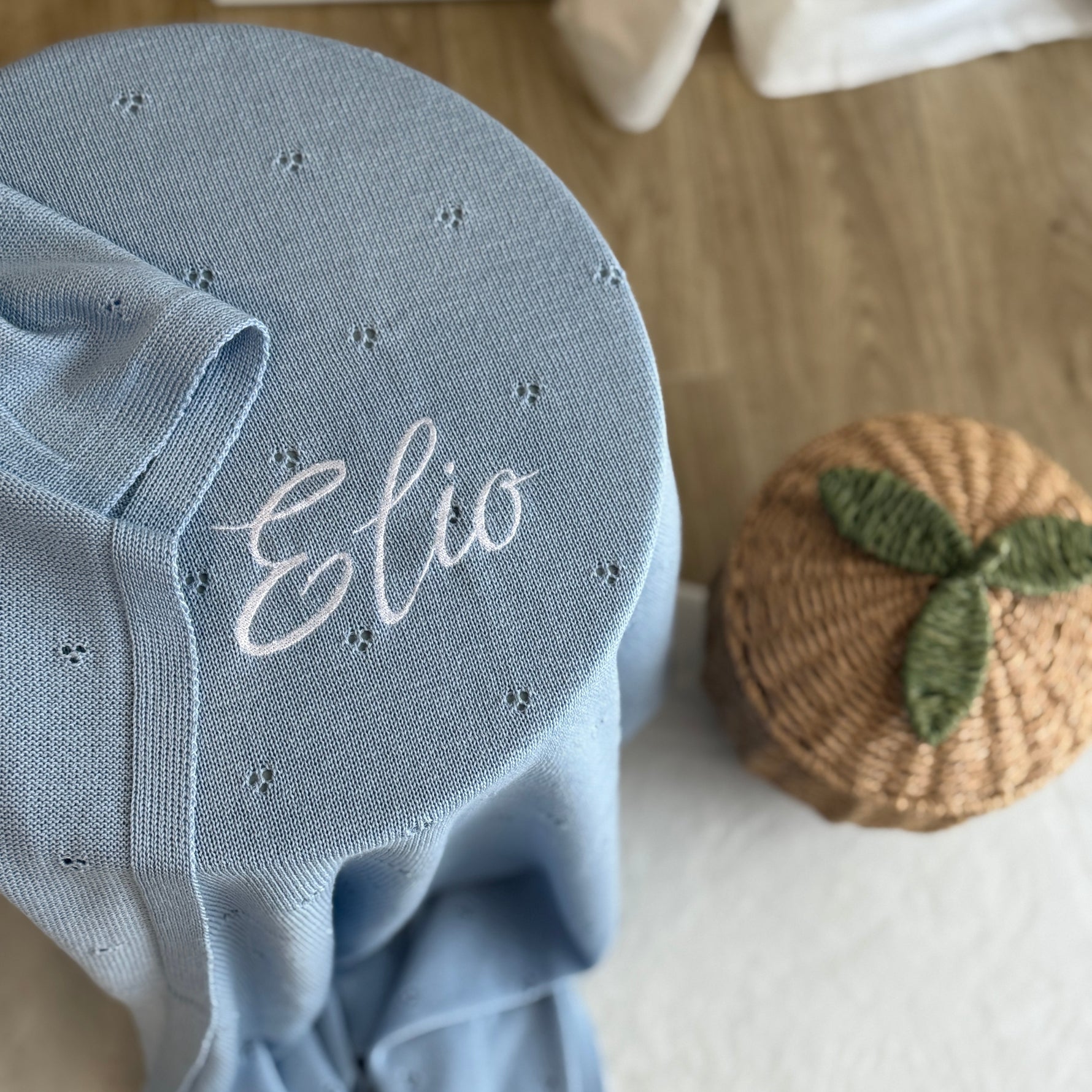 Blue baby bonnet with 'Elio' embroidery on a light background