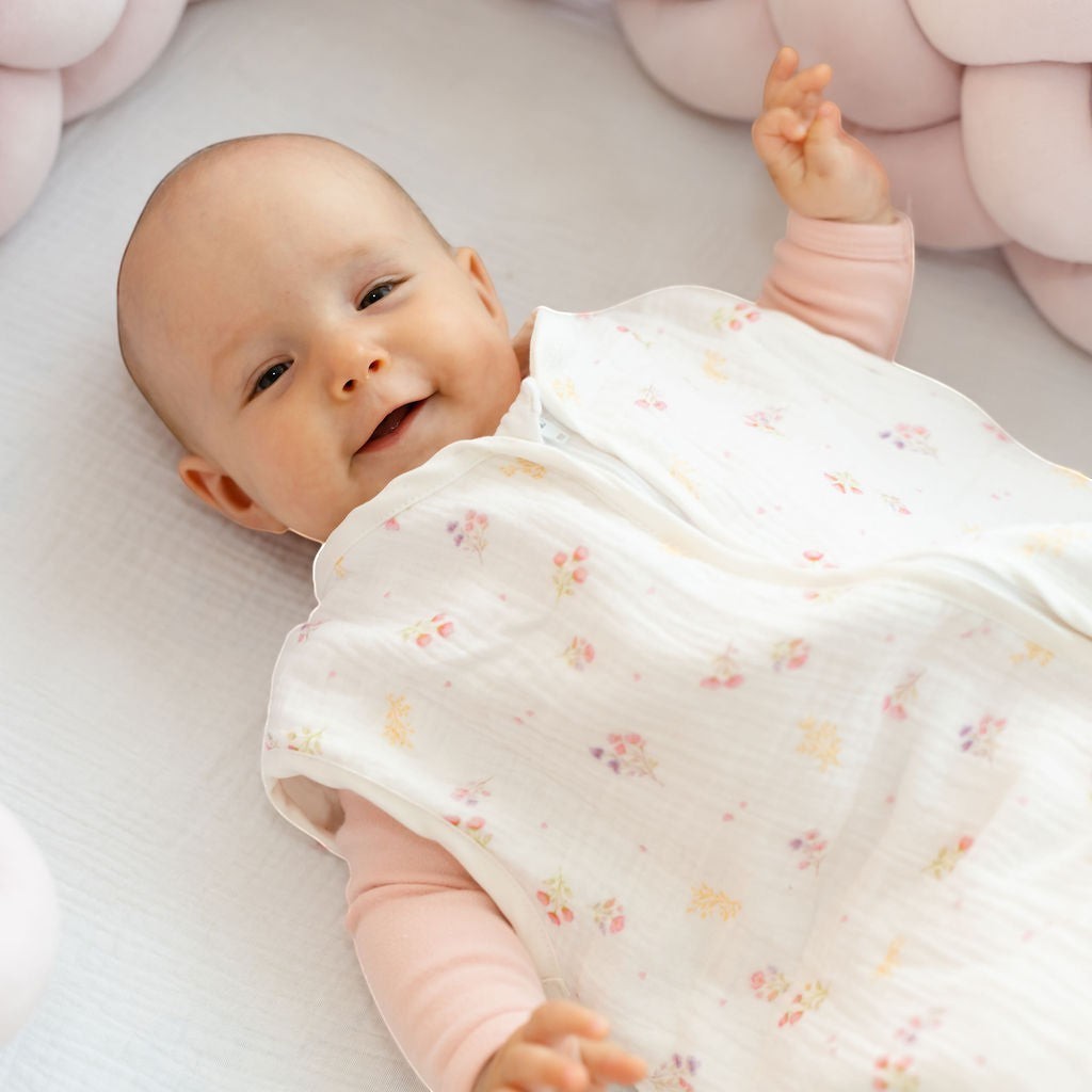Baby Natur sleeveless sleeping bag with floral print, made from soft, breathable cotton. Pink long-sleeve shirt underneath.