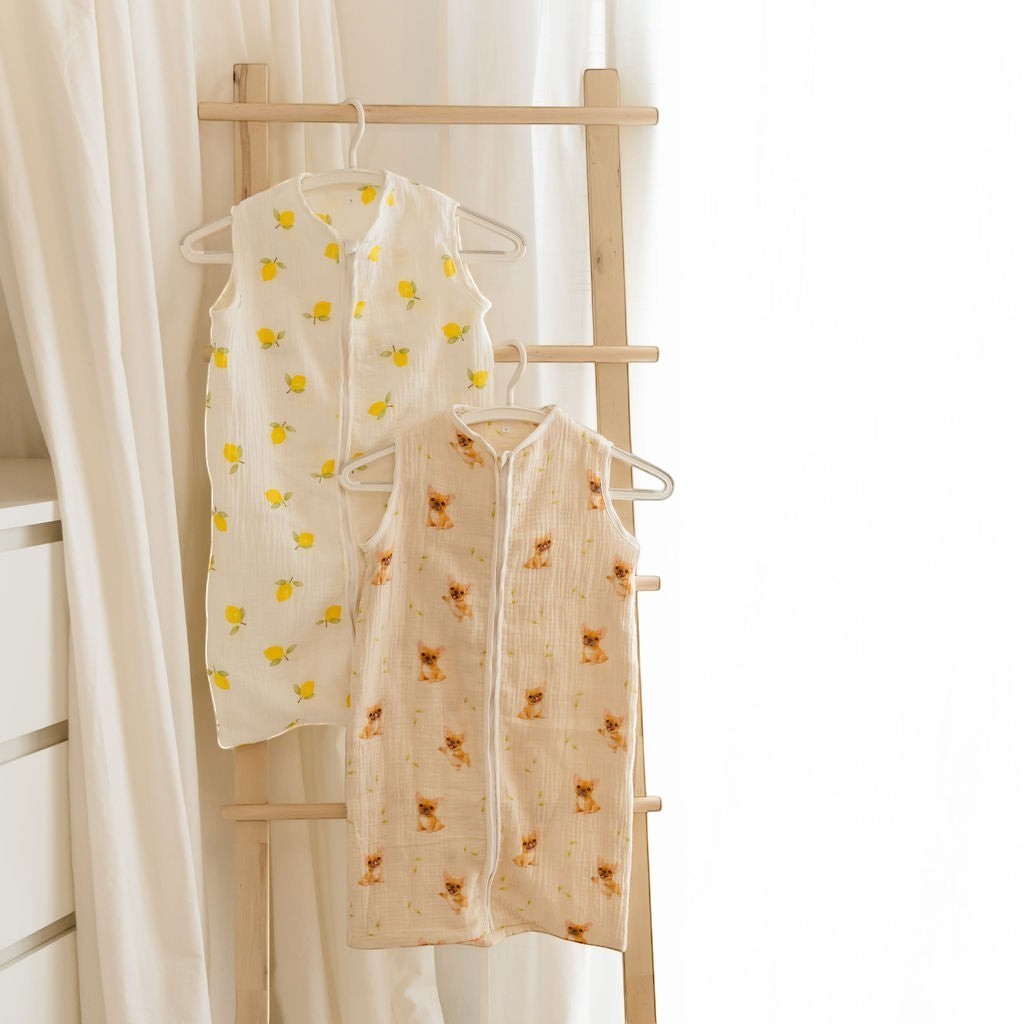 Baby Natur sleeveless sleeping bags in white with lemon print and beige with dog print. Made from soft, natural materials.