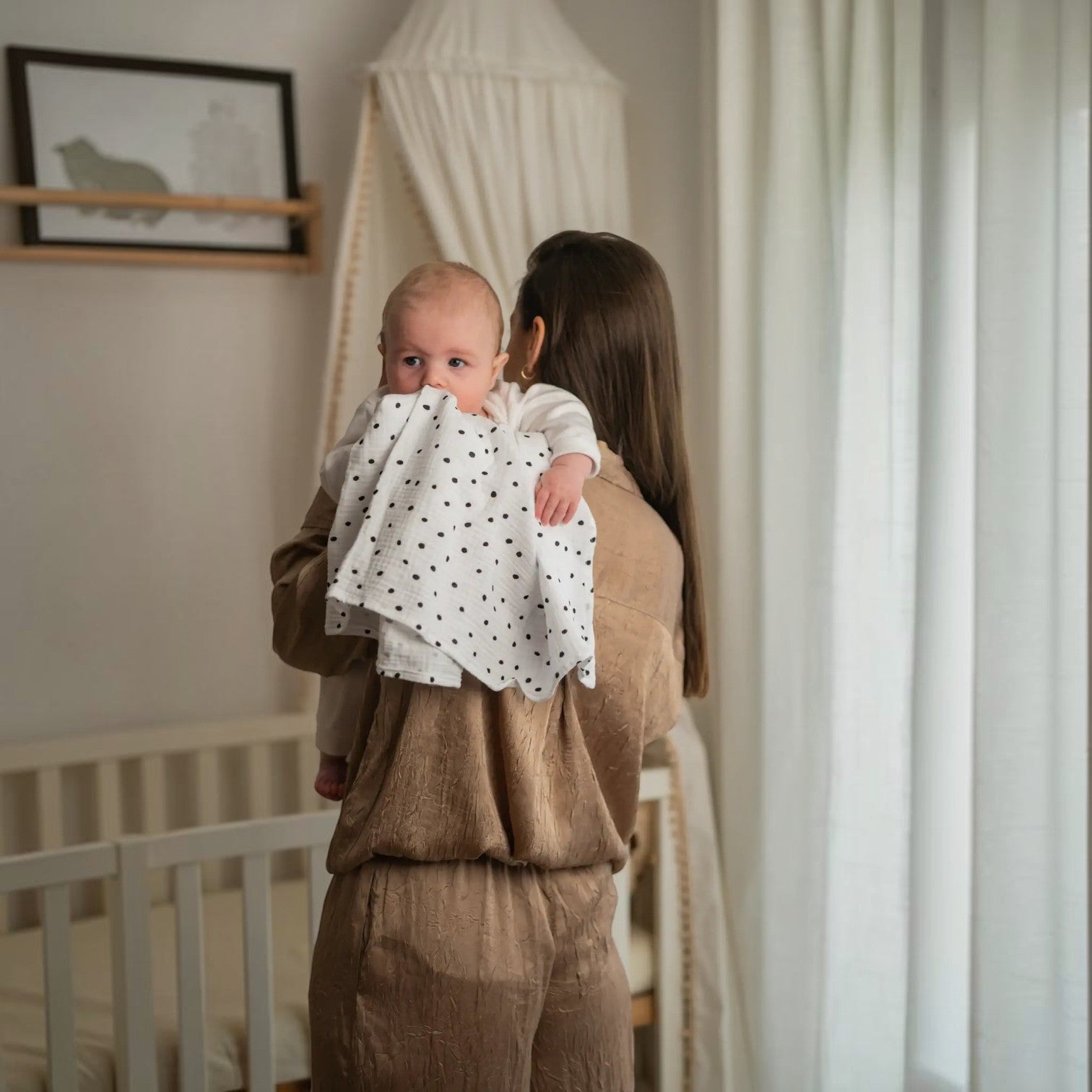 Baby NaturHere standard tetra diaper made of 100% cotton with black polka dots, used by a mother to burp her baby.